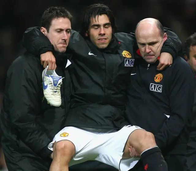 Tévez cargado por médicos del Manchester United.