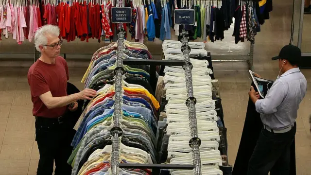 Hombres mirando ropa en una tienda de segunda mano.
