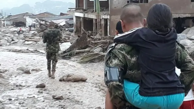 சிறுமி ஒருவரை பாதுகாப்பான இடத்திற்கு சுமந்து கொண்டு செல்லும் மீட்புப்படையினர்
