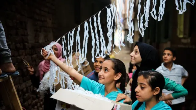 أطفال يعلقون زينة رمضان