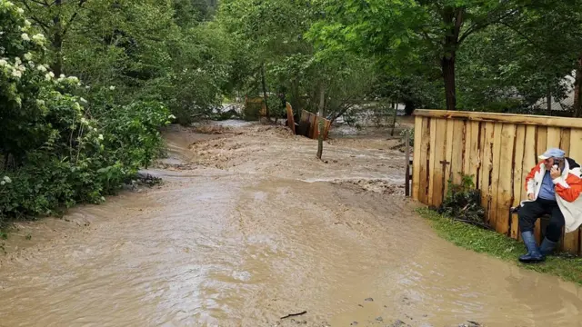 человек сидит у забора на затопленной улице