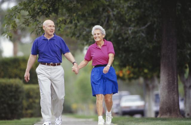 Un couple âgé se promenant dans un quartier de banlieue