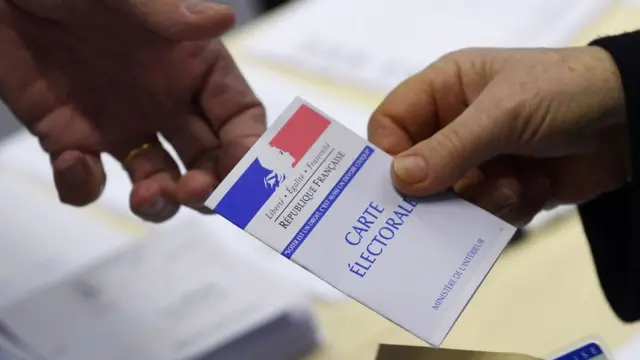 法国雷恩一名选民将选民登记证交予投票站职员查验（23/4/2017）