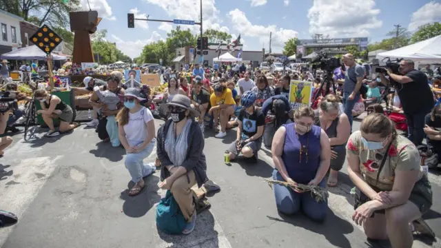 Diversas personas con la rodilla apoyada en el suelo en el aniversario de la muerte de George Floyd.