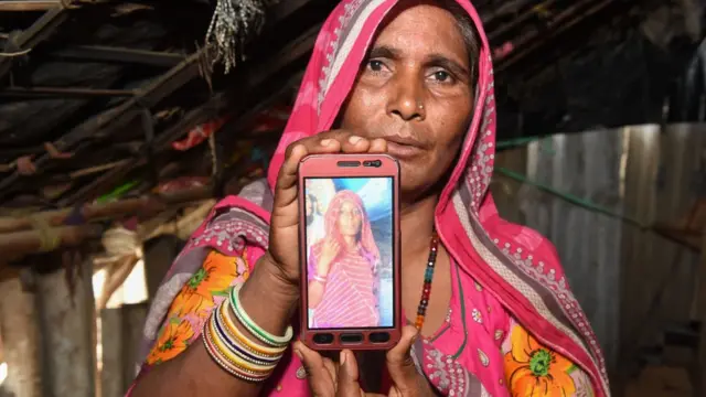 এই নারী তার মোবাইল ফোনে একজন আত্মীয়ের ছবি দেখাচ্ছেন যাকে ছেলেধরা গুজবের জের ধরে পিটিয়ে হত্যা করা হয়েছে।