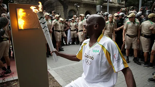 O gari Renato Sorriso acende o primeiro dos cinco marcos olímpicos