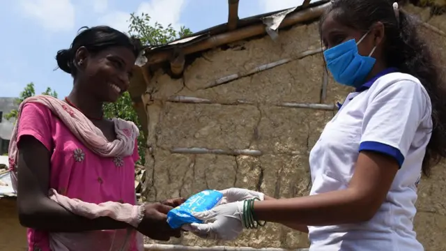 Muni Gupta passing a blue bag to a woman