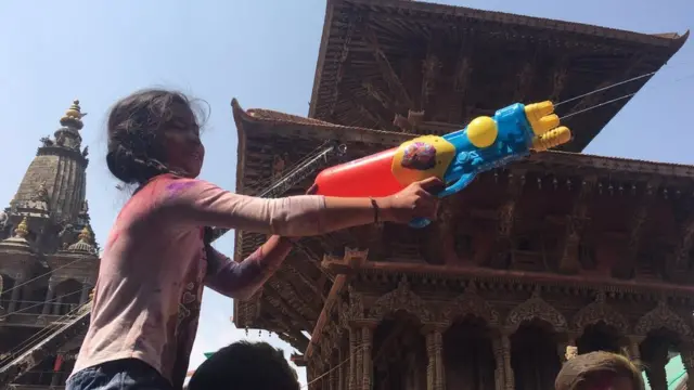 पिचकारीबाट पानी फ्याक्दै एक बालिका।