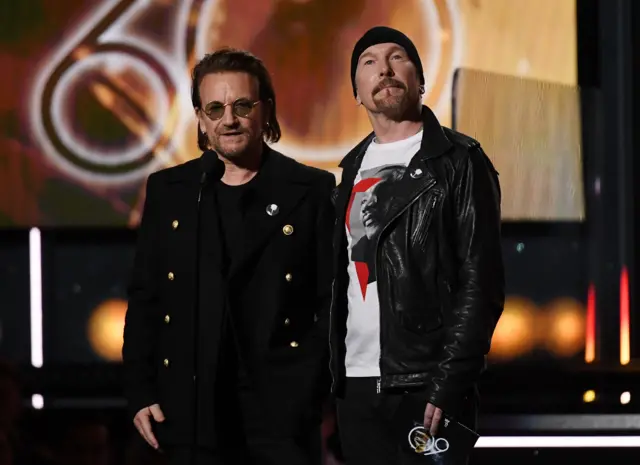 Bono and The Edge from U2 stand on stage