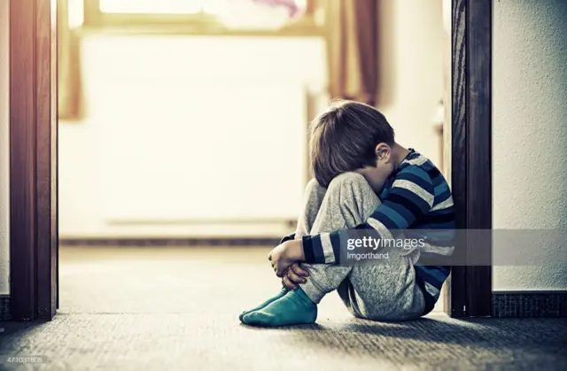 طفل يحلس على الارض ويغطي وجهه