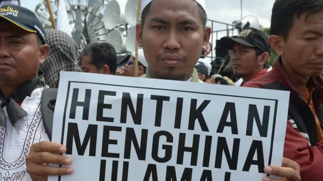 pengunjuk rasa dengan poster hentikan menghina ulama