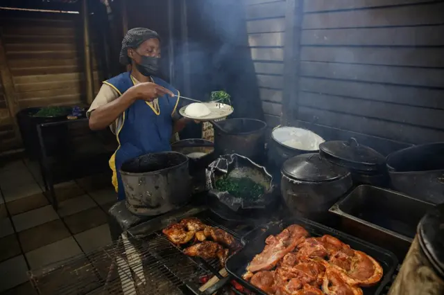 A chef dishes up a traditional meal of Sadza and green vegetables for a customer at the popular Little Mereki restaurant in Harare, Zimbabwe, 08 April 2022.