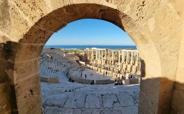Un amphithéâtre romain vu à travers une arche.