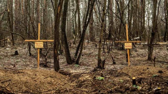Duas pequenas cruzes de madeira marcam os túmulos de Petro e Veronika na floresta