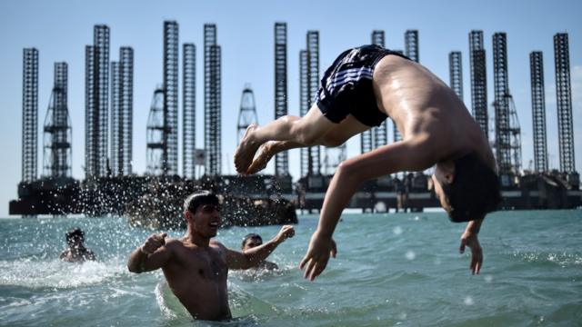 Teenagers from a boxing school take part in a training session on the shores of the Caspian Sea near Soviet oil rigs in the Azerbaijani capital Baku on June 27, 2015.