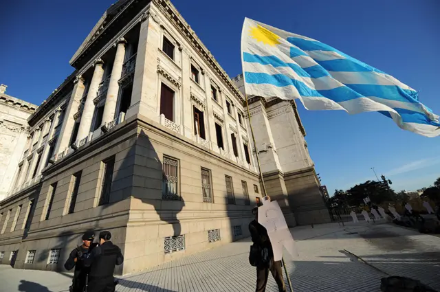 Un hombre sostiene una bandera fuera del Parlamento uruguayo en Montevideo.