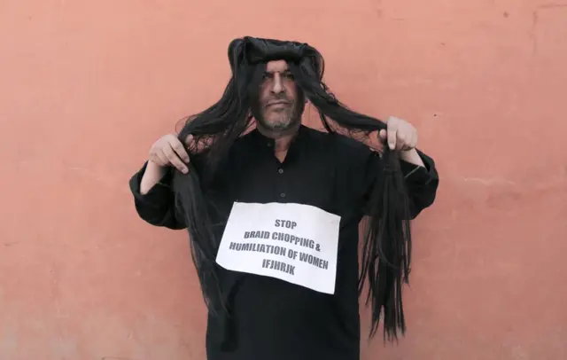 احسن انٹو نے احتجاج کرتے ہوئے وگ پہن رکھی ہے