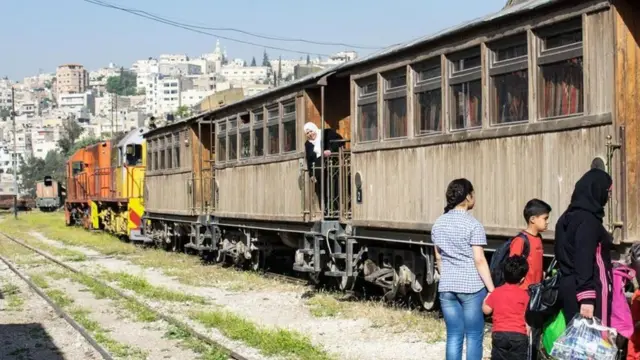 أم وأبناؤها ينتظرون ركوب القطار