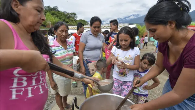 Dos mujeres sirven tazones de chocolate a los niños.