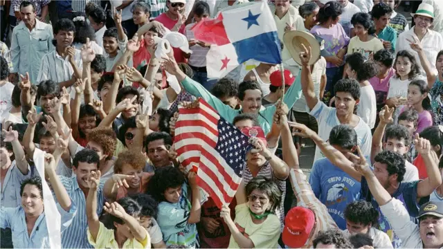 Abanyagihugu batishimira ubutegetsi bwa General Manuel Antonio Noriega bakirije abasirikare ba Amerika amabendera ya Amerika na Panama, aho hari kuwa 22/12/1989.
