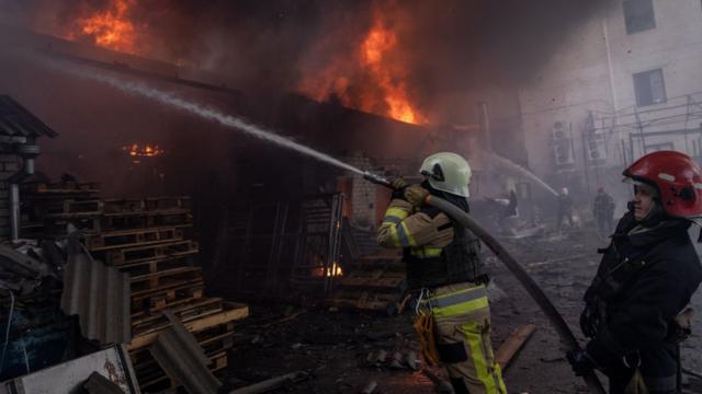 Пожарные пытаются потушить здание склада в Харькове, загоревшееся после российских обстрелов