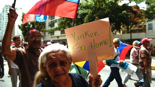 Una mujer en Caracas con una pancarta que dice: Yankee go home!
