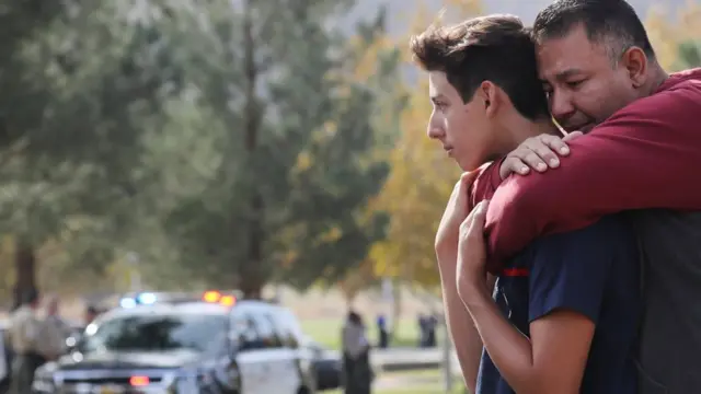 총격이 발생한 학교 주차장에서 생사를 확인한 학생을 학부모가 안고 있다