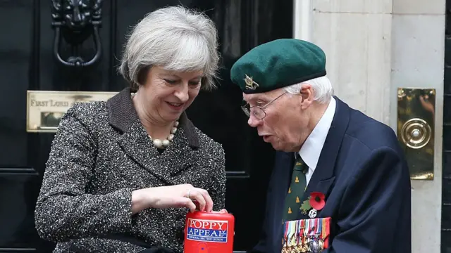 Başbakan Theresa May bir gönüllüden gelincik satın alırken.