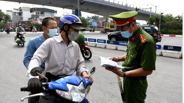 Công an kiểm tra giấy tờ một người đi đường ở Hà Nội (Hình chụp ngày 29/7)