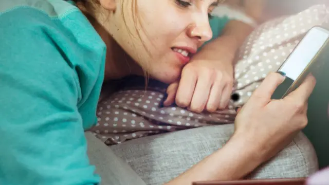 Teenage girl using her phone in bed