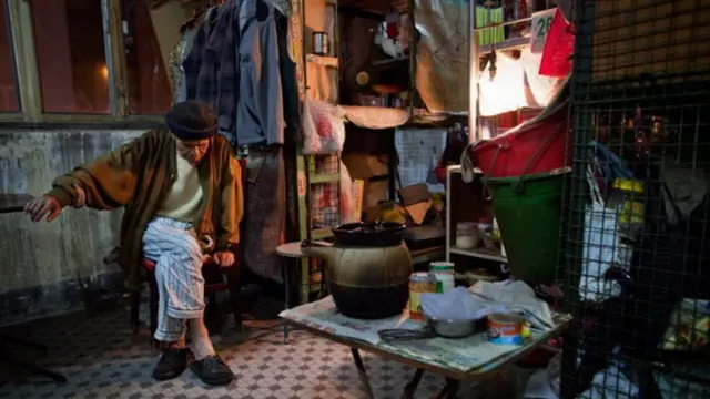 ชายวัย 78 ปีนั่งอยู่ภายในที่พักที่มีสภาพเหมือนกรง