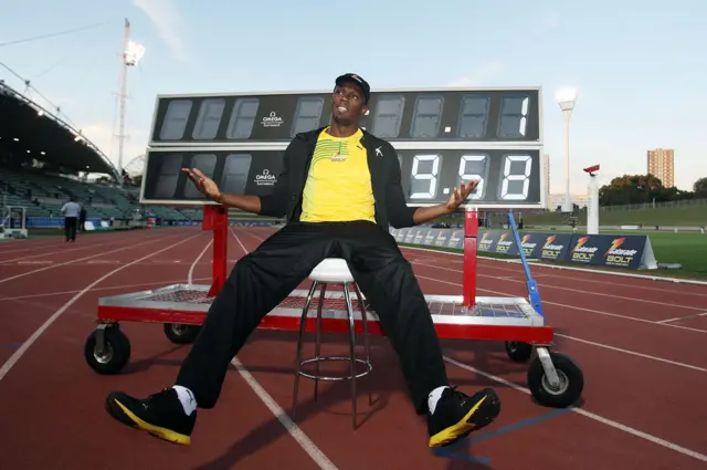Usain Bolt frente a un cartel que muestra su récord de los 100 metros.