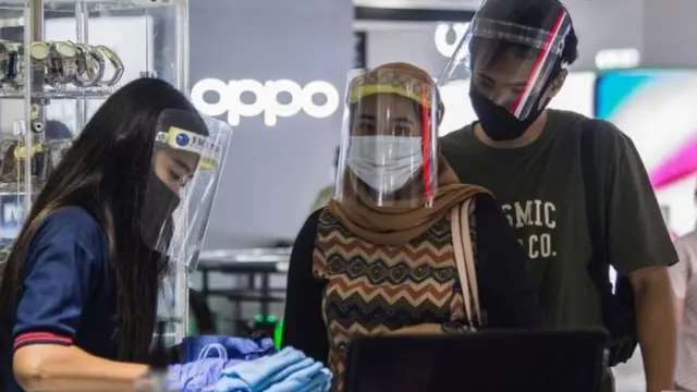 Pelanggan di toko di Surabaya mengenakan masker.