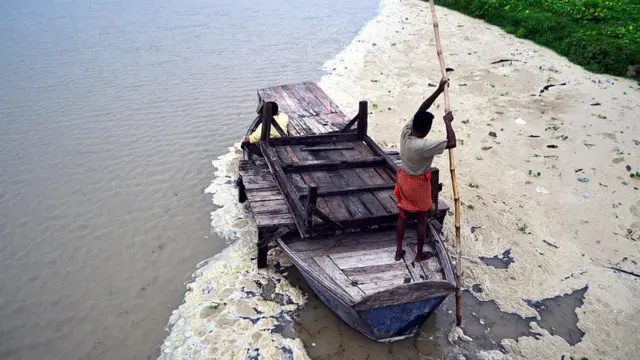 પ્રયાગરાજમાં કૅમિકલથી પ્રદૂષિત પાણીમાં બોટ ચલાવી રહેલા માછીમારની તસવીર