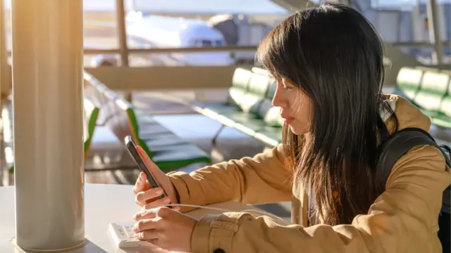 Una mujer con un teléfono celular en un aeropuerto.