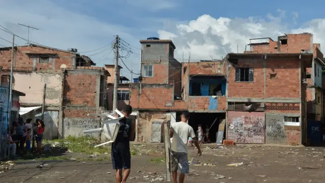 Jovens caminham pela favela do metrô mangueira