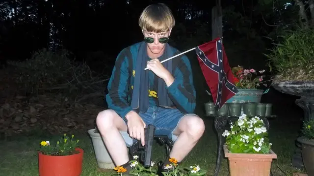 Dylann Roof sosteniendo un arma y una bandera confederada