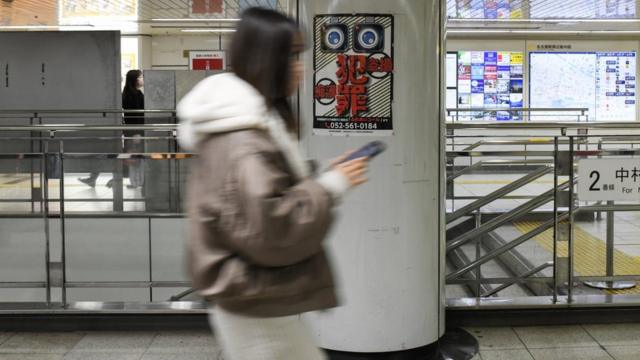 A woman walks past an anti-Chikan poster on the Tokyo metro