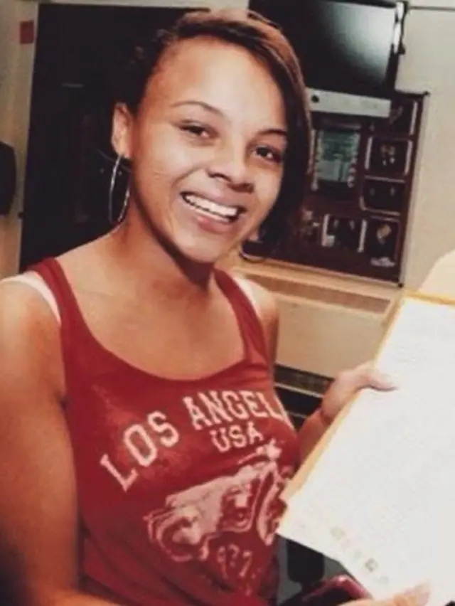 A young Alexandra smiling, holding her exam results