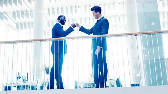 Dos personas vestidas de ejecutivas chocando las manos