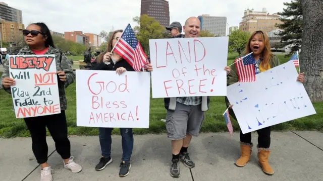 Protesters hold signs encouraging people to demand that businesses be allowed to open up in Kansas City, Missouri.