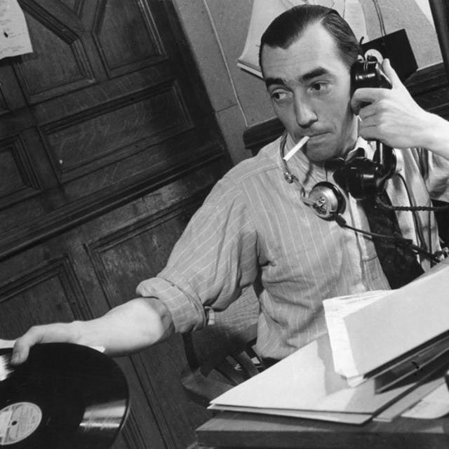 Periodista en el Servicio Latinoamericano hablando por teléfono y con un disco de pasta en la mano, en 1940
