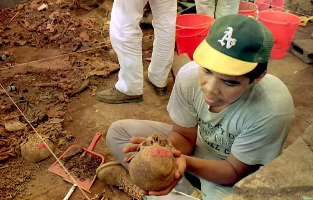 Hombre sostiene un cráneo extraído de El Mozote en 1992.