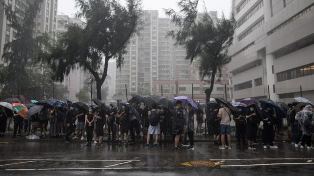 香港早上发出台风警告，支持者打着伞在法院大楼外等候。