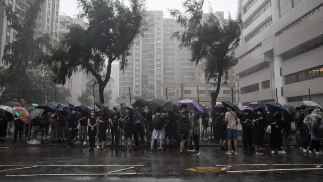 香港早上发出台风警告,支持者打着伞在法院大楼外等候。
