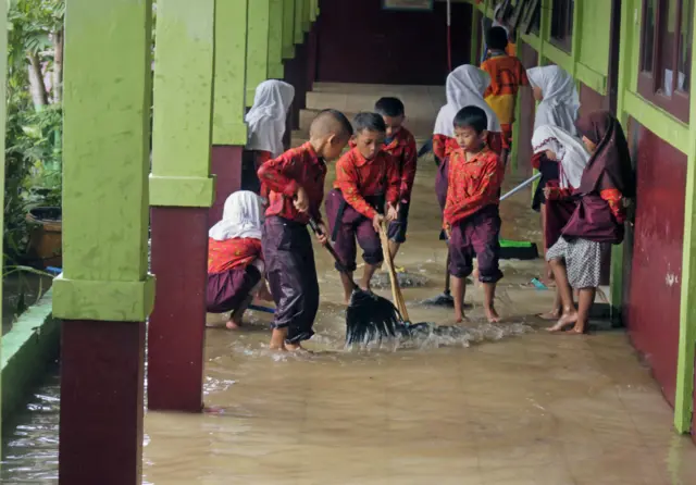 Sejumlah siswa mengeringkan genangan air di bangunan sekolahnya yang terendam banjir di SD Negeri Pamarican, di Kampung Kasemen, Serang, Banten, Rabu (05/02).