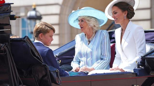 Príncipe George, a Duquesa da Cornualha e a Duquesa de Cambridge (à direita) em uma carruagem puxada por cavalos