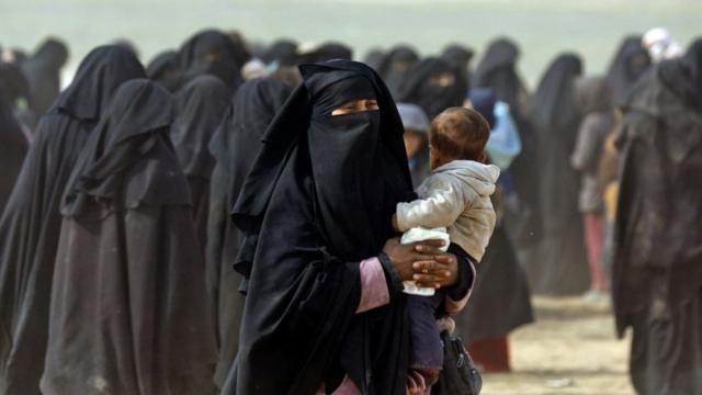 Mujer escapando con su hijo de un territorio que era controlado por el EI.