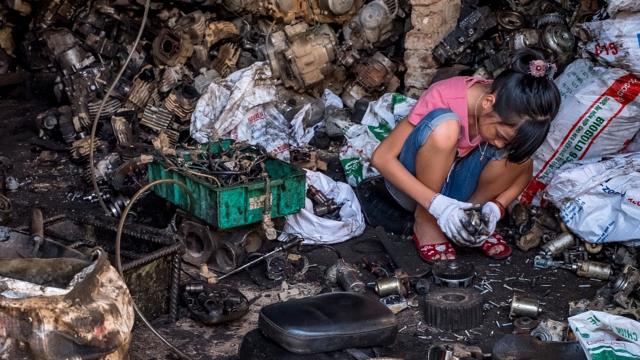 Adolescente reciclando componentes de baterías y otros desechos electrónicos en Vietnam