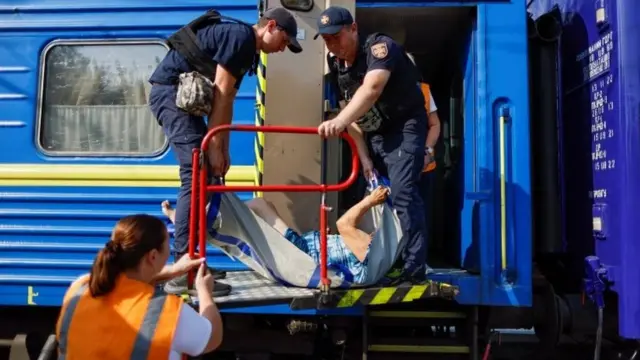 Волонтери та рятувальники допомагають евакуюватися літній жінці